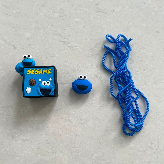 Blue fuzzy monster charger adapter cover, mini monster cable bite and blue coil winder - flat lay on white surface