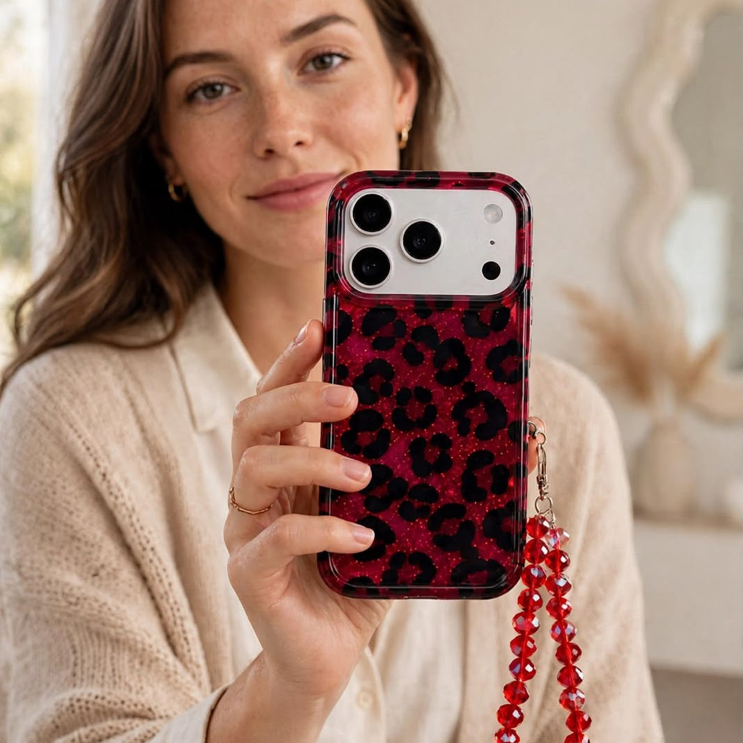 Woman holding red leopard print iPhone case up to ear with crystal bead charm dangling