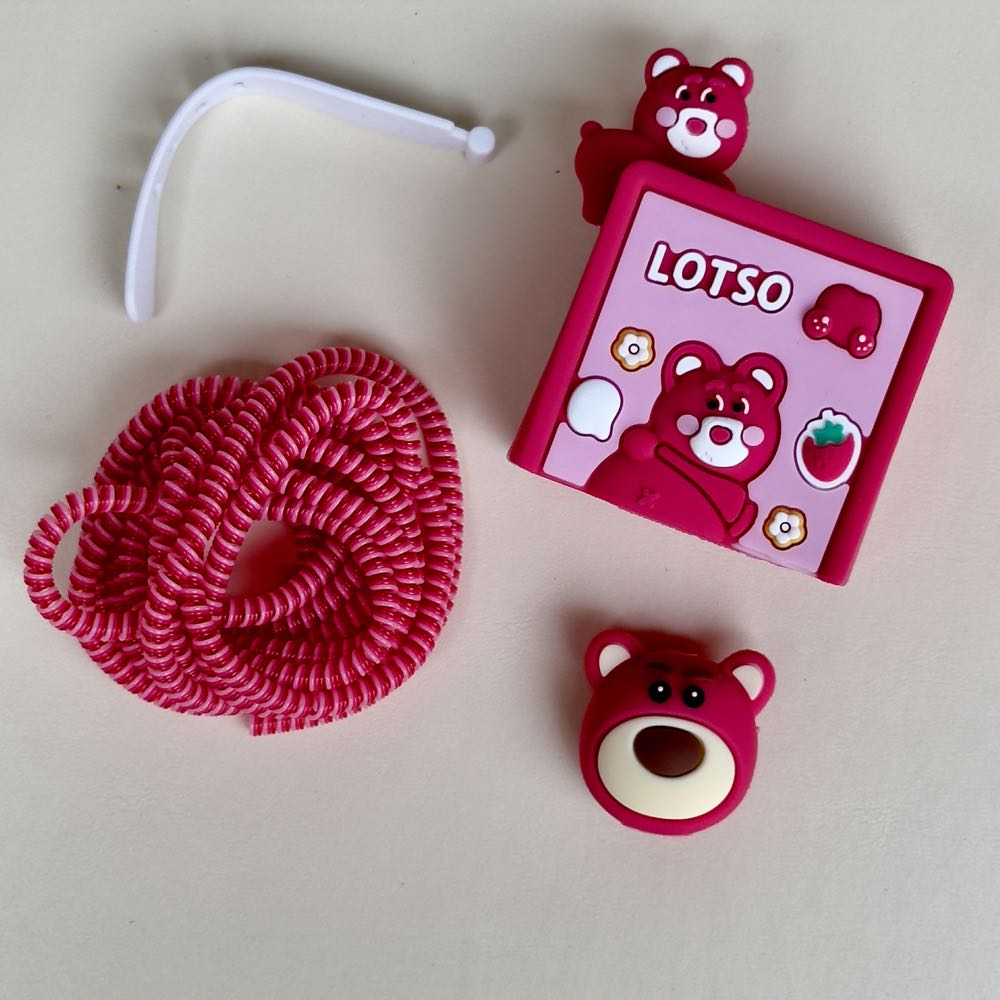 Strawberry bear charger adapter cover with pink coil cable winder and bear cable bite - flat lay