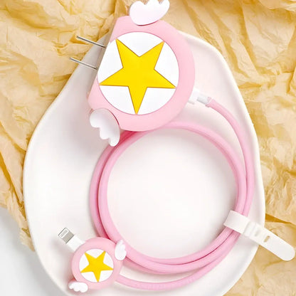 Pink winged star charger cover and mini cable protector with pink spiral cable wrap flat lay on white surface next to pink bowl