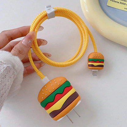Burger iPhone charger adapter cover and mini cable protector with yellow coil winder held in hand against white wall