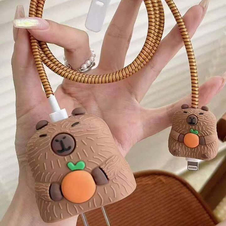 Capybara charger adapter cover on power strip with golden coil winder on wooden desk - warm lifestyle shot