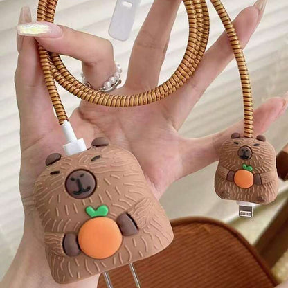 Capybara charger adapter cover on power strip with golden coil winder on wooden desk - warm lifestyle shot