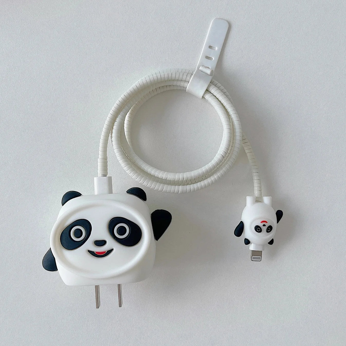 3D panda face charger cover with white spiral cable wrap and mini panda cable protector flat lay