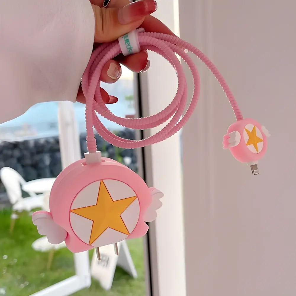 Pink winged star charger cover and mini cable protector held in hand outdoors with green grass background