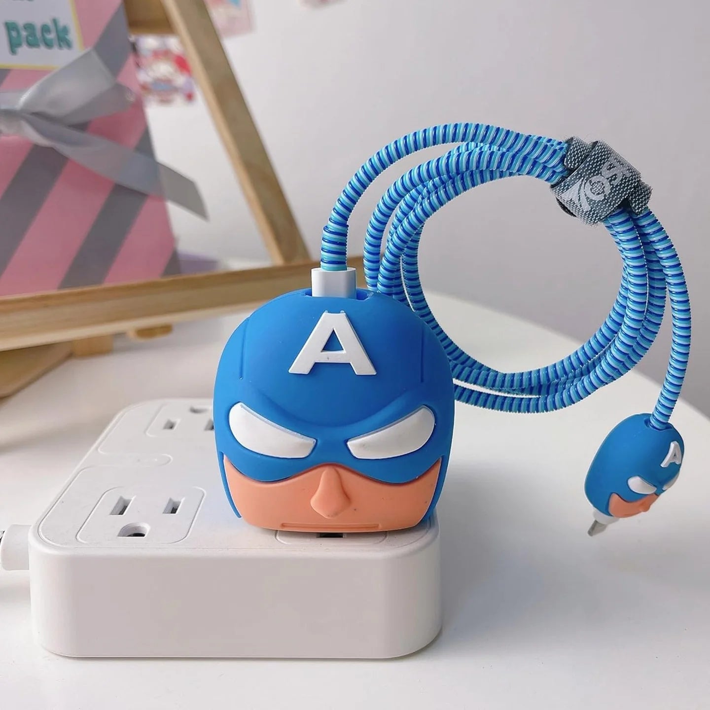 Blue hero mask charger cover and cable protector held in hand