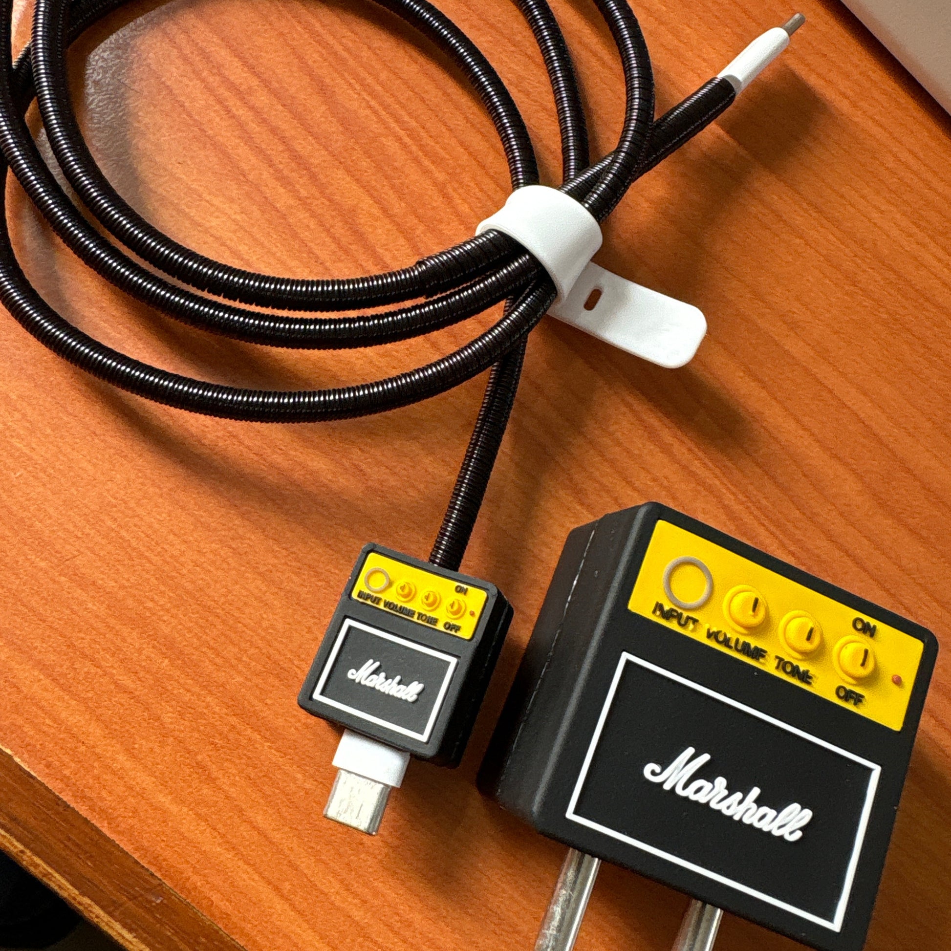 Rock amp charger adapter cover on white desk with black coil winder and mini amp cable bite - lifestyle shot
