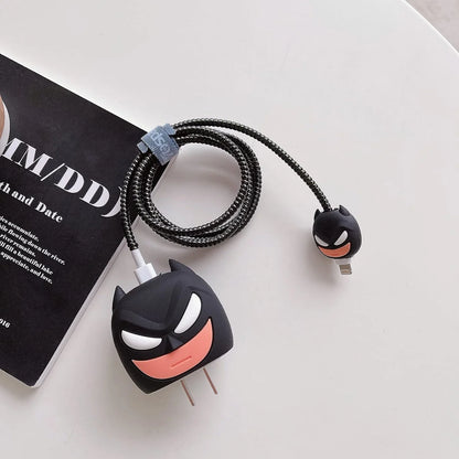 Dark masked hero charger cover and mini cable protector with black spiral cable wrap on white surface next to magazine