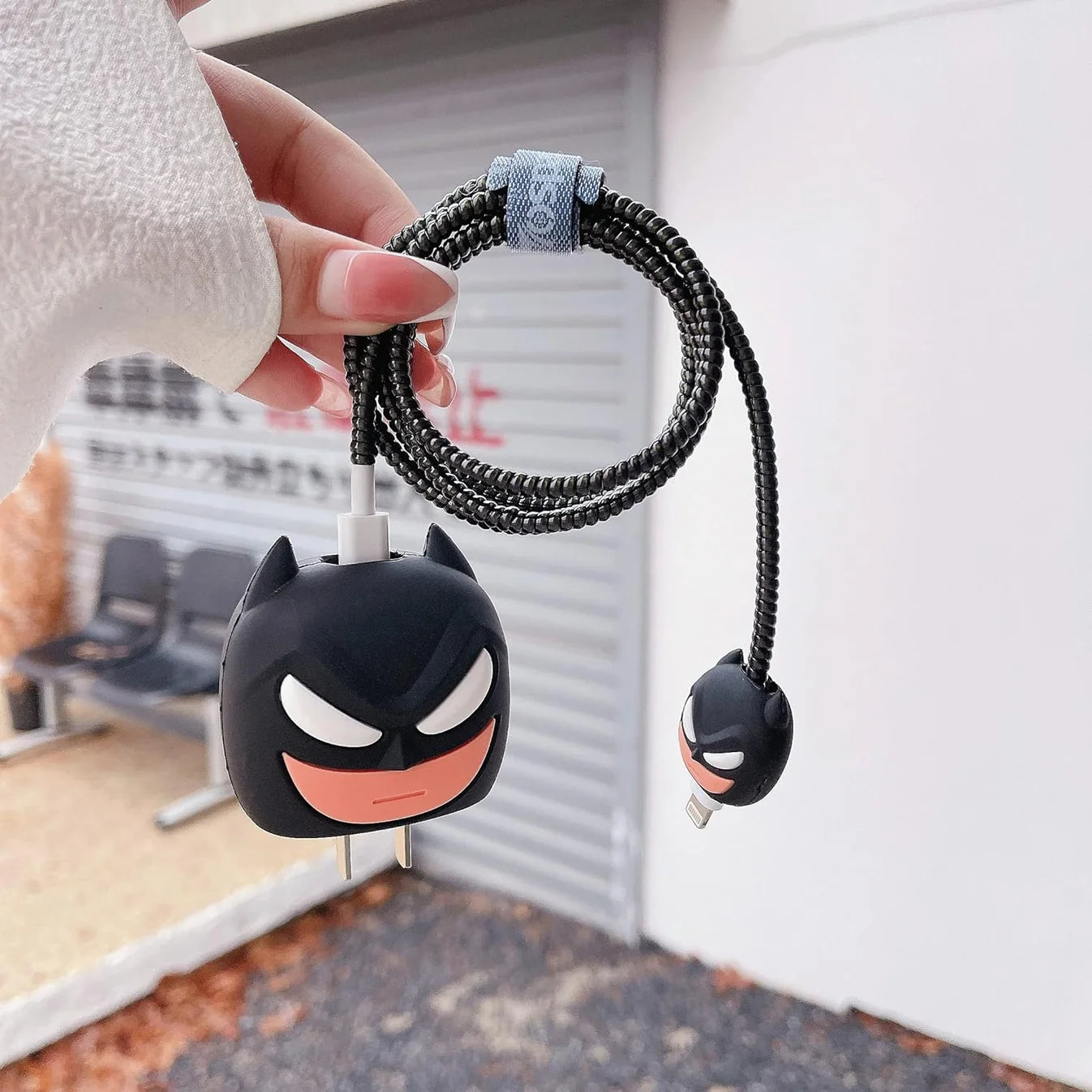 Dark masked hero charger cover and mini cable protector with black spiral cable wrap held in hand outdoors