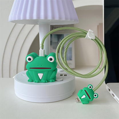 Green frog charger adapter cover and mini frog cable protector with green spiral cable wrap on white desk