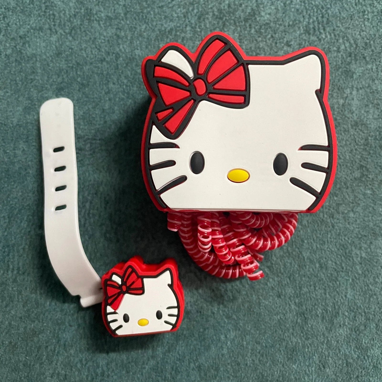 Bow kitty charger adapter cover and mini cable bite with red coil winder - lifestyle shot on teal background