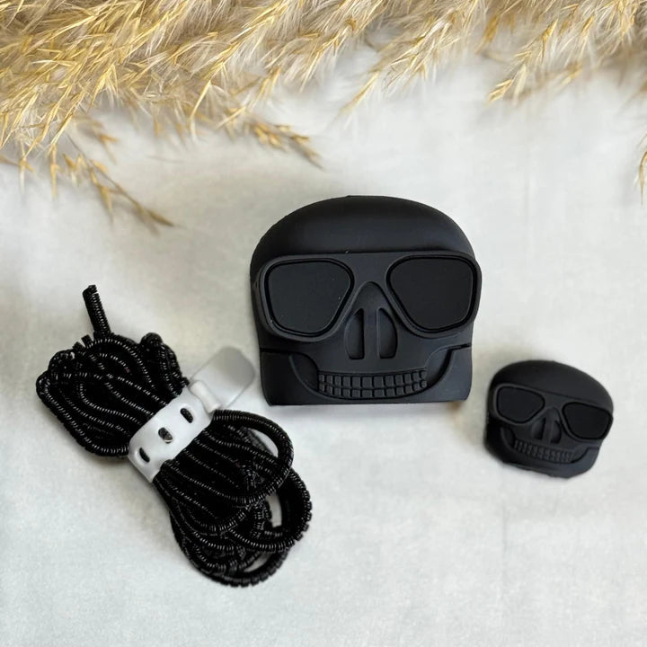 Skull AirPods case flat lay with cable protector and spiral lanyard on white surface