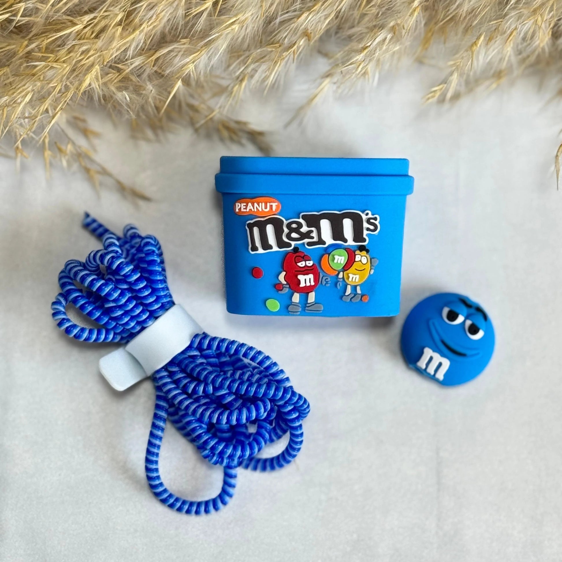 Blue candy box charger cover and mini round candy cable protector with blue spiral cable wrap on white fur surface with dried grass background