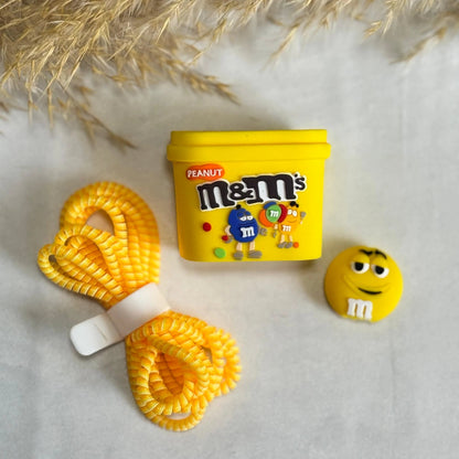 M&M's Peanut charger adapter cover, M&M character cable bite, and yellow coil winder - flat lay