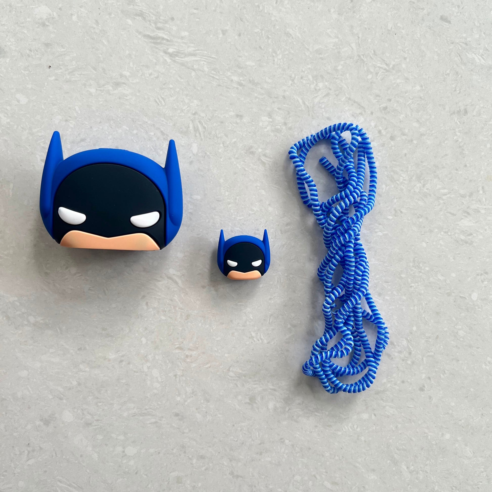 Batman silicone charger adapter cover with mini cable protector and blue coil lanyard on white surface