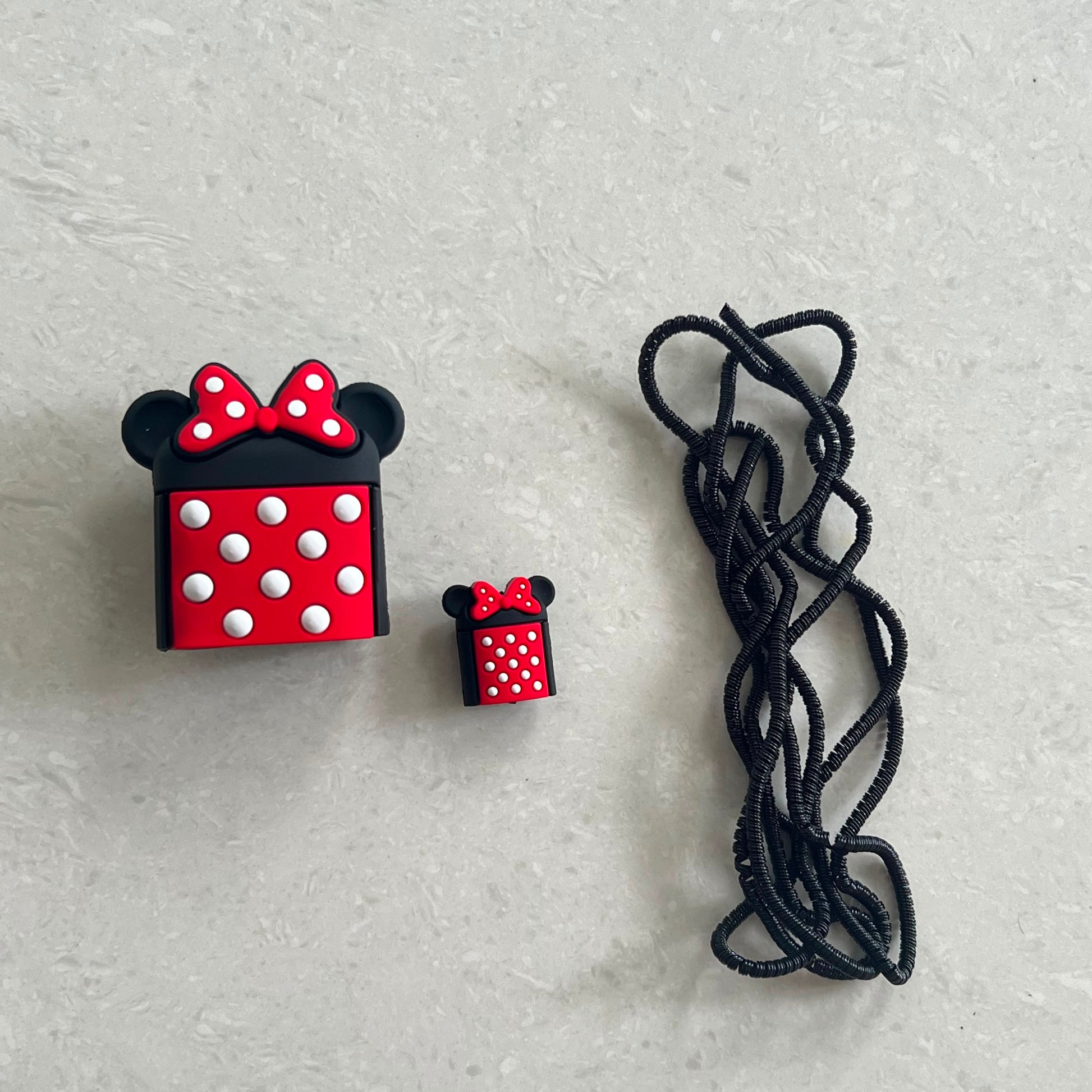 Bow mouse charger adapter cover, mini cable protector and black spiral cable winder flat lay on white surface