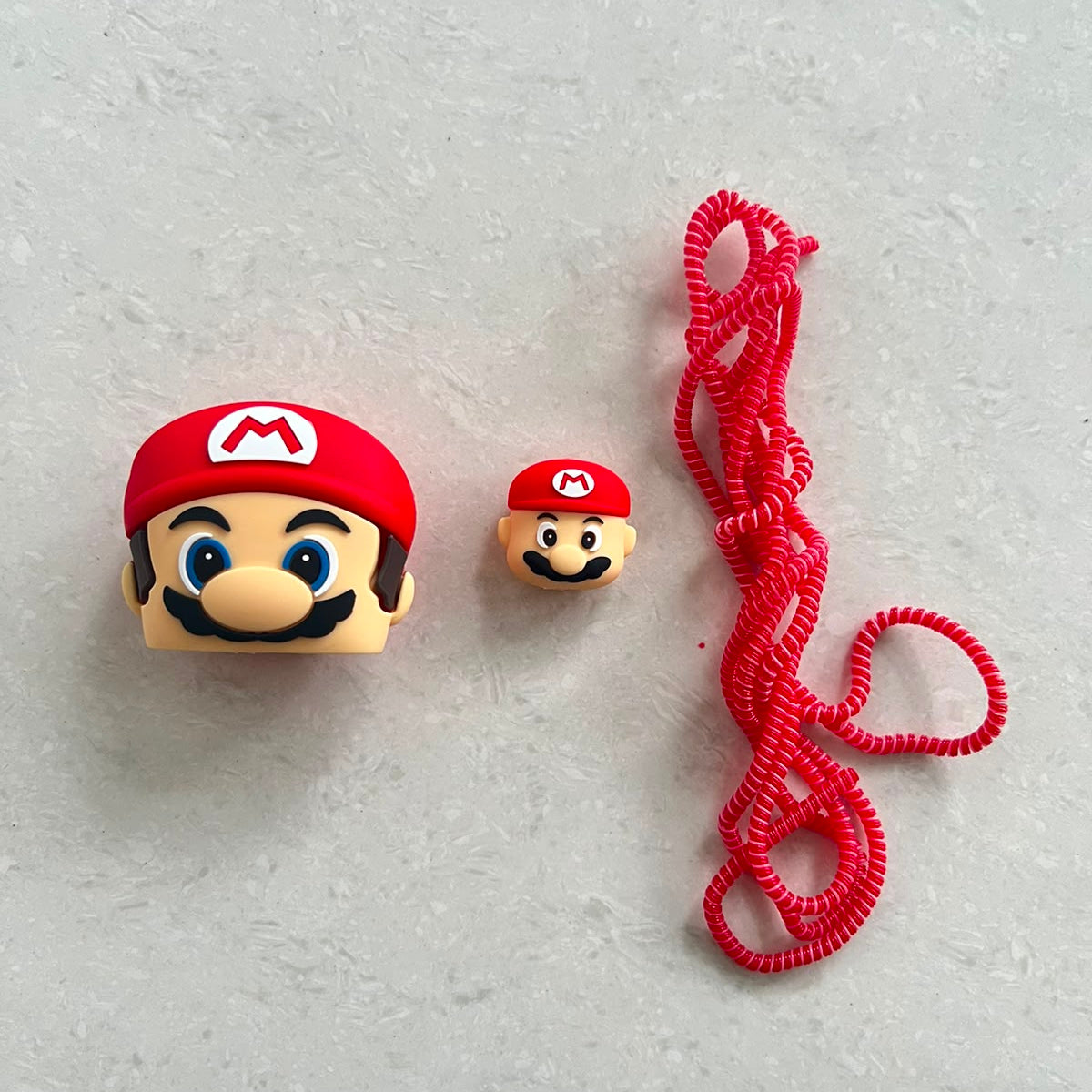 Red cartoon character charger adapter cover and mini cable protector components laid out on white surface