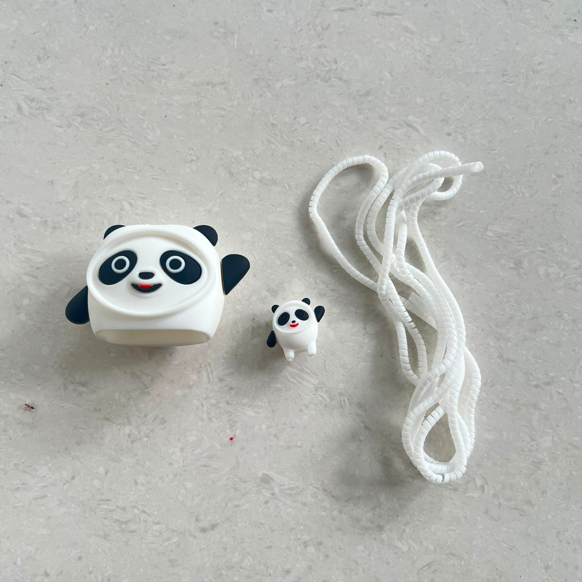 Mini panda cable protector and panda charger cover components laid flat on white surface