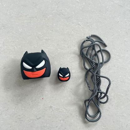 Dark masked hero charger adapter cover, mini cable protector and black spiral cable wrap components flat lay on grey surface