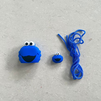 Blue fuzzy monster charger adapter cover, mini cable protector and blue spiral cable wrap components flat lay on grey surface