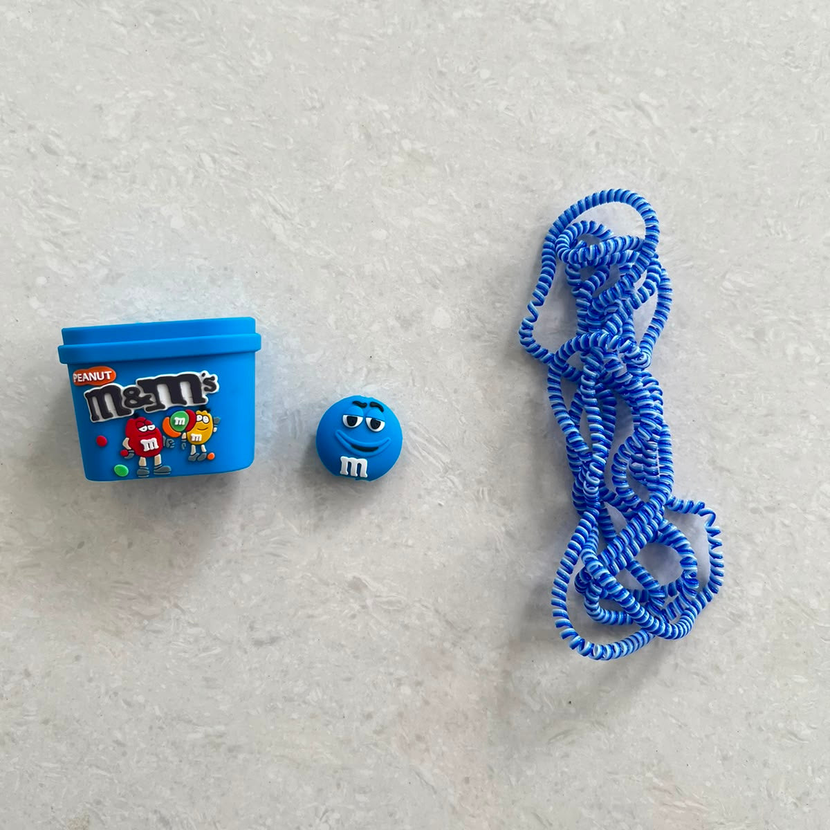 Blue candy box charger adapter cover, mini round candy cable protector and blue spiral cable wrap components flat lay on white surface