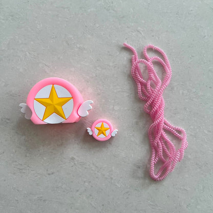 Pink winged star charger adapter cover, mini cable protector and pink spiral cable wrap components flat lay on grey surface