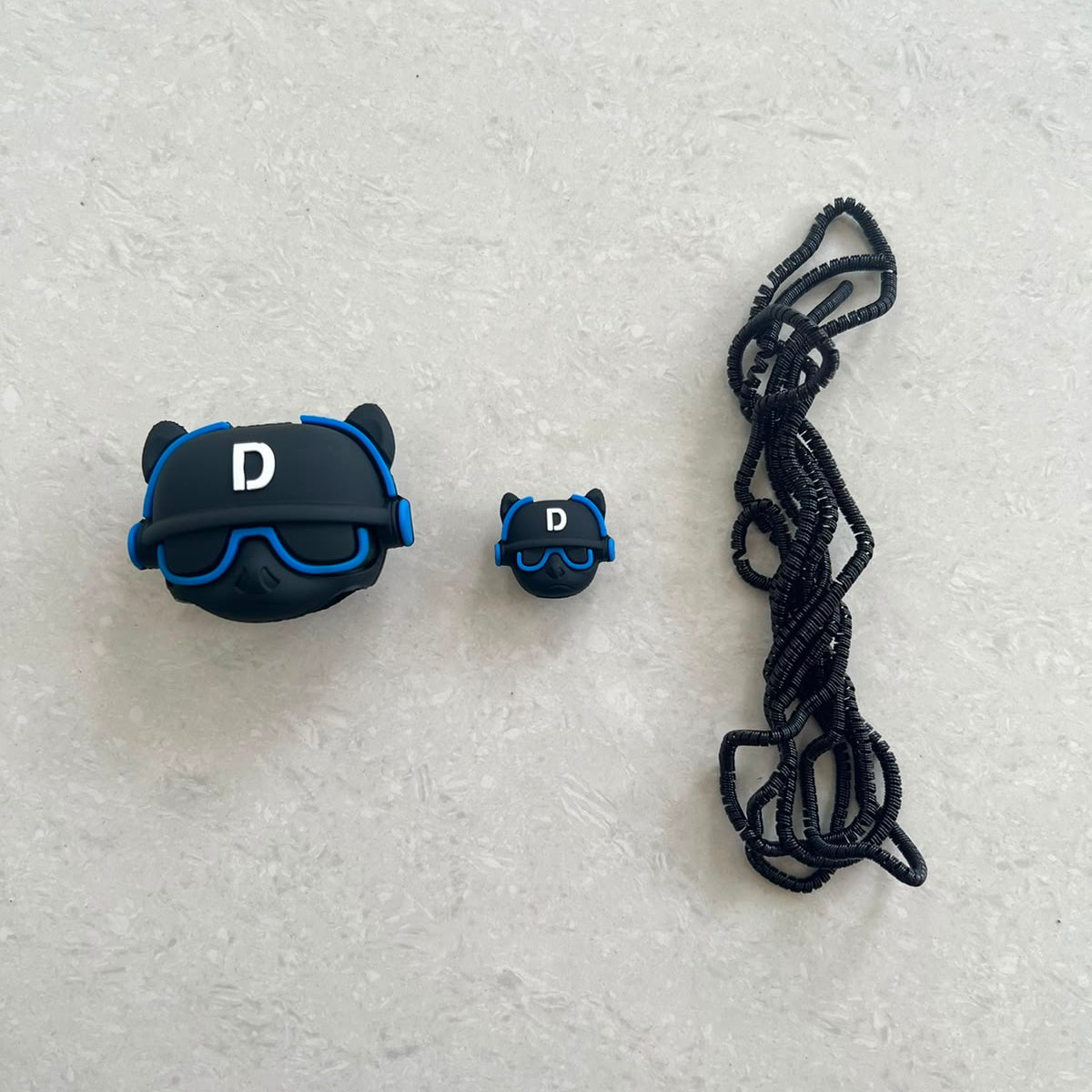Dark grey bulldog DJ charger adapter cover, mini bulldog cable protector and black spiral cable wrap flat lay on white surface