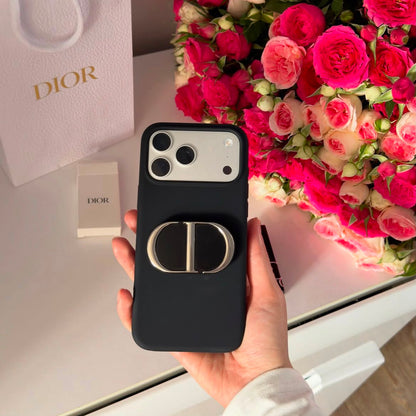 Monogram phone grip attached to black iPhone case with roses in background