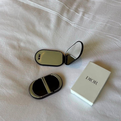 Compact mirror phone grip open on white bedsheet with gift box