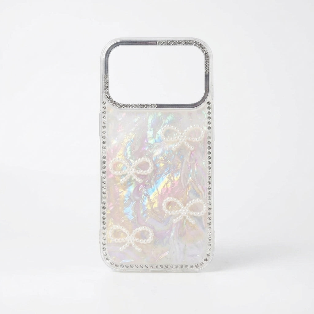 Two iPouch Pearl Shell Bow iPhone Cases side by side with crystal bead wristlets on cream fabric
