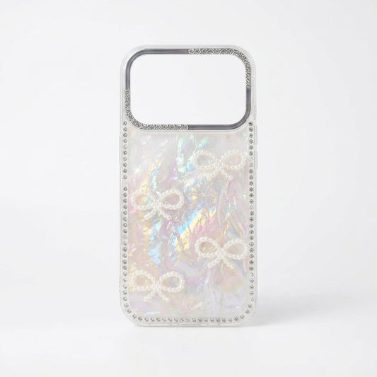 Two iPouch Pearl Shell Bow iPhone Cases side by side with crystal bead wristlets on cream fabric