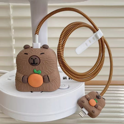 Capybara charger adapter cover and mini cable bite held in hand with golden coil winder - lifestyle shot