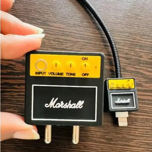 Rock amp charger adapter cover held in hand showing yellow control panel with knobs detail - close up